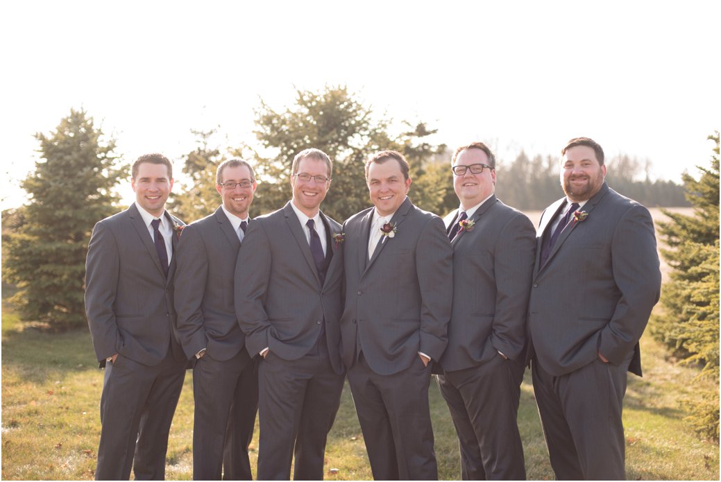 groomsmen in three piece suits with plum ties
