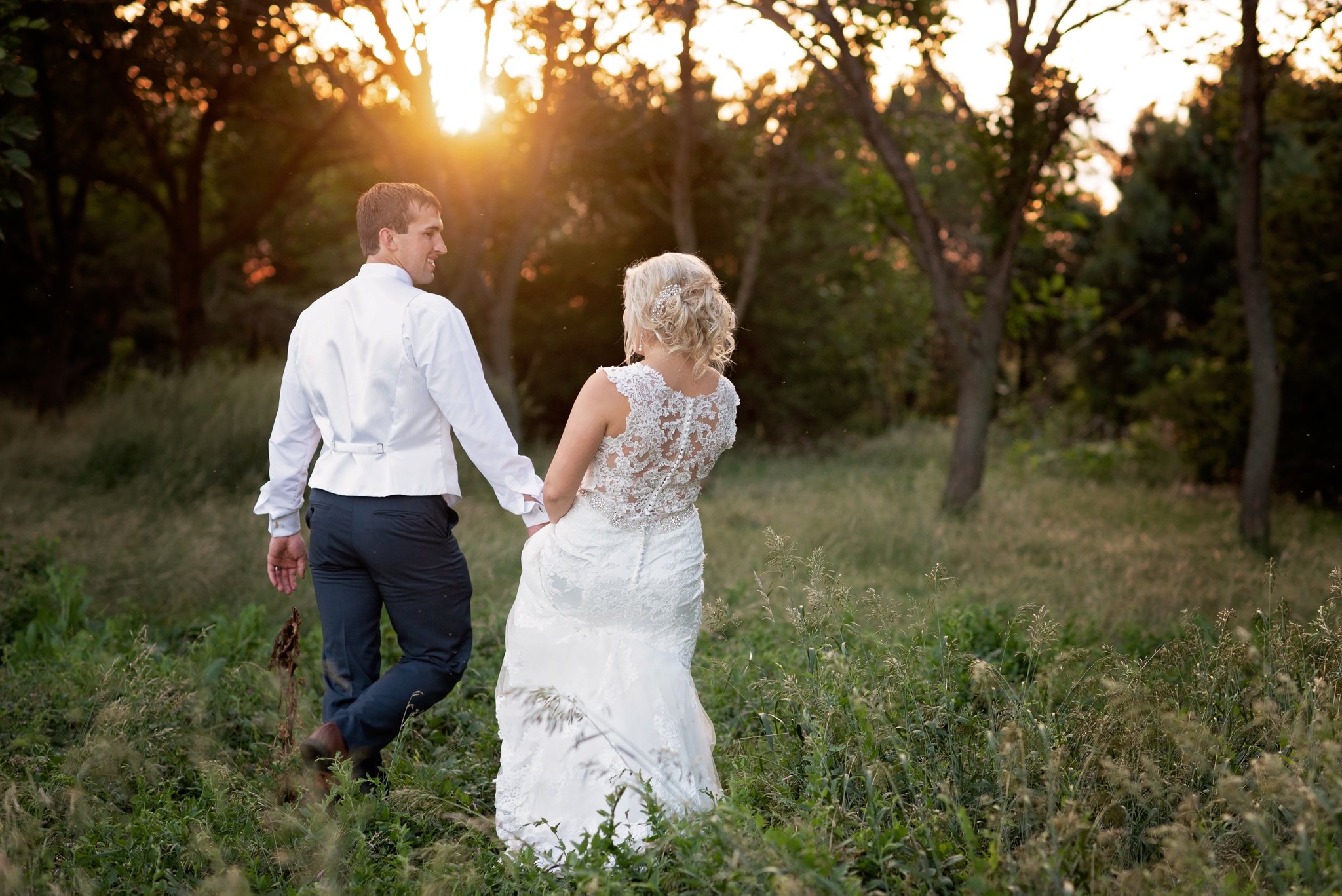 groom leads bride into the sunset