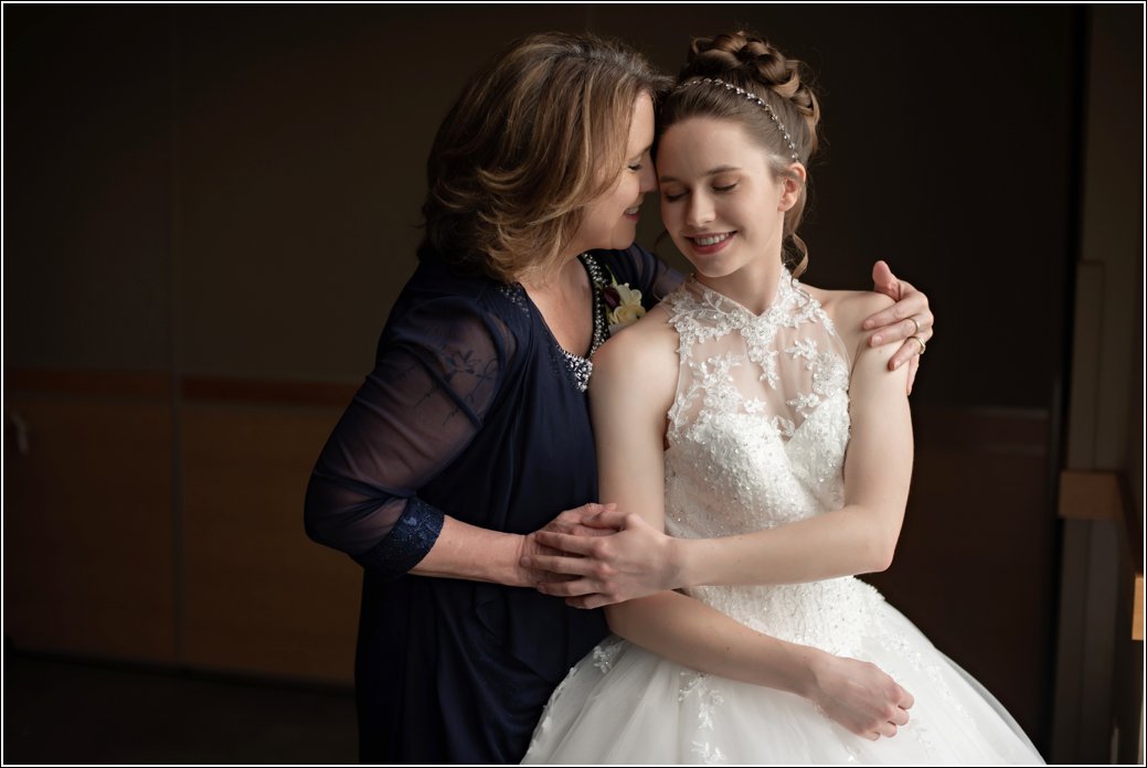 mom helps bride get dressed for wedding in beaded gown