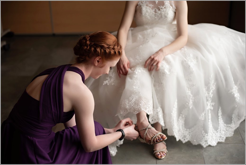 redhead bridesmaid in purple dress helps bride
