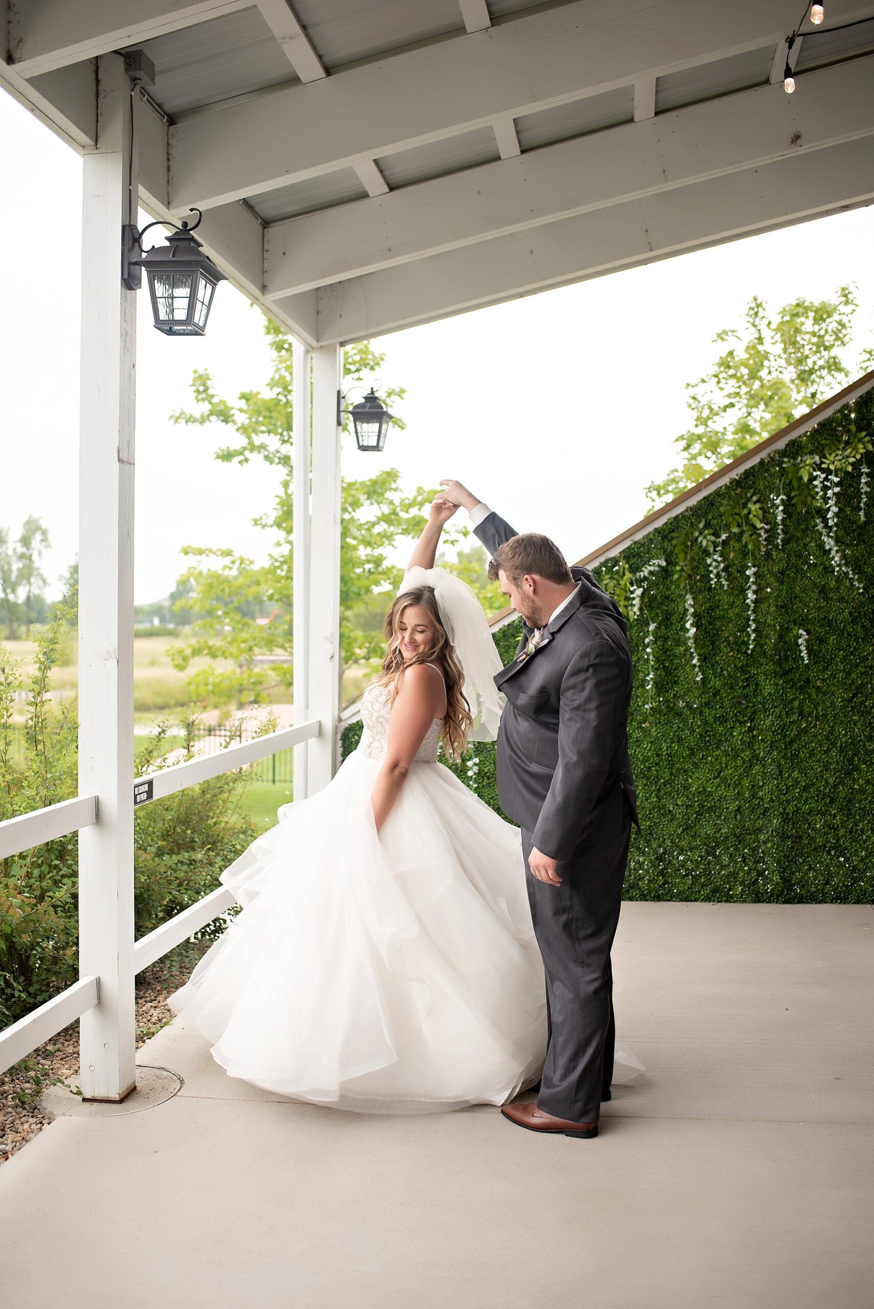 groom twirls the bride on covered porch blue haven barn and gardens