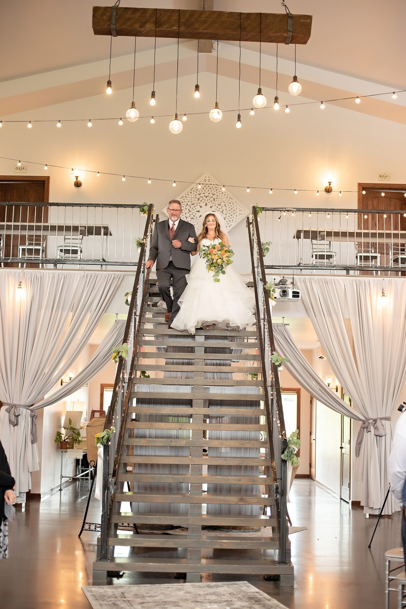 bride walks down staircase at blue haven barn and gardens