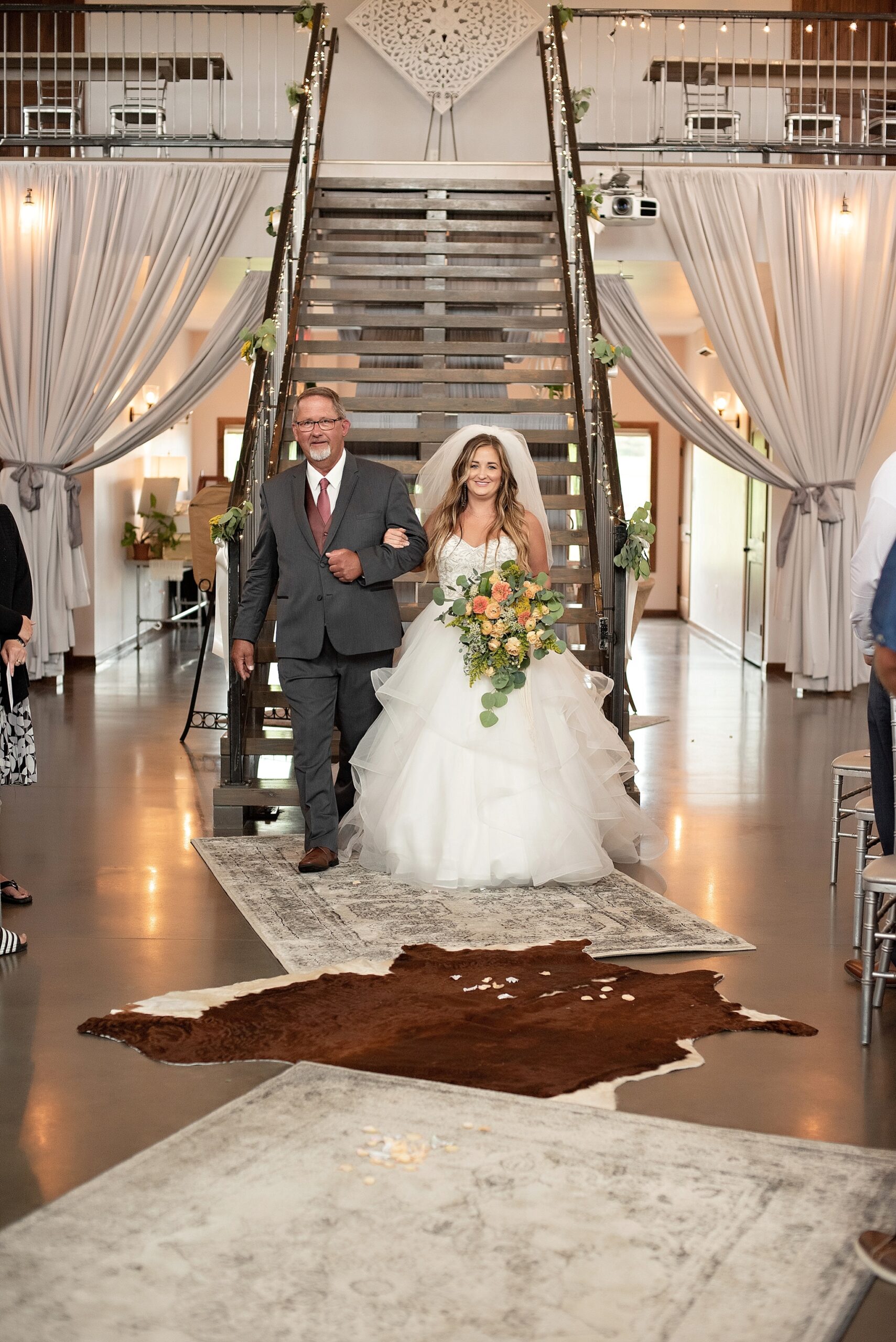 father of the bride escorts the bride down a staircase blue haven barn sioux falls south dakota