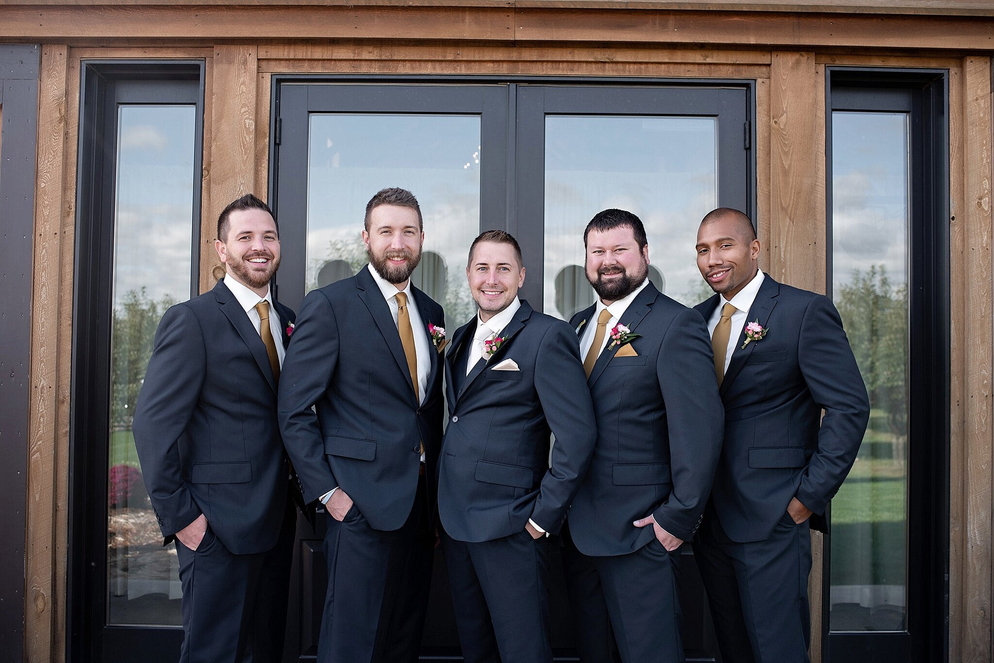 groomsmen in navy tuxes with gold ties