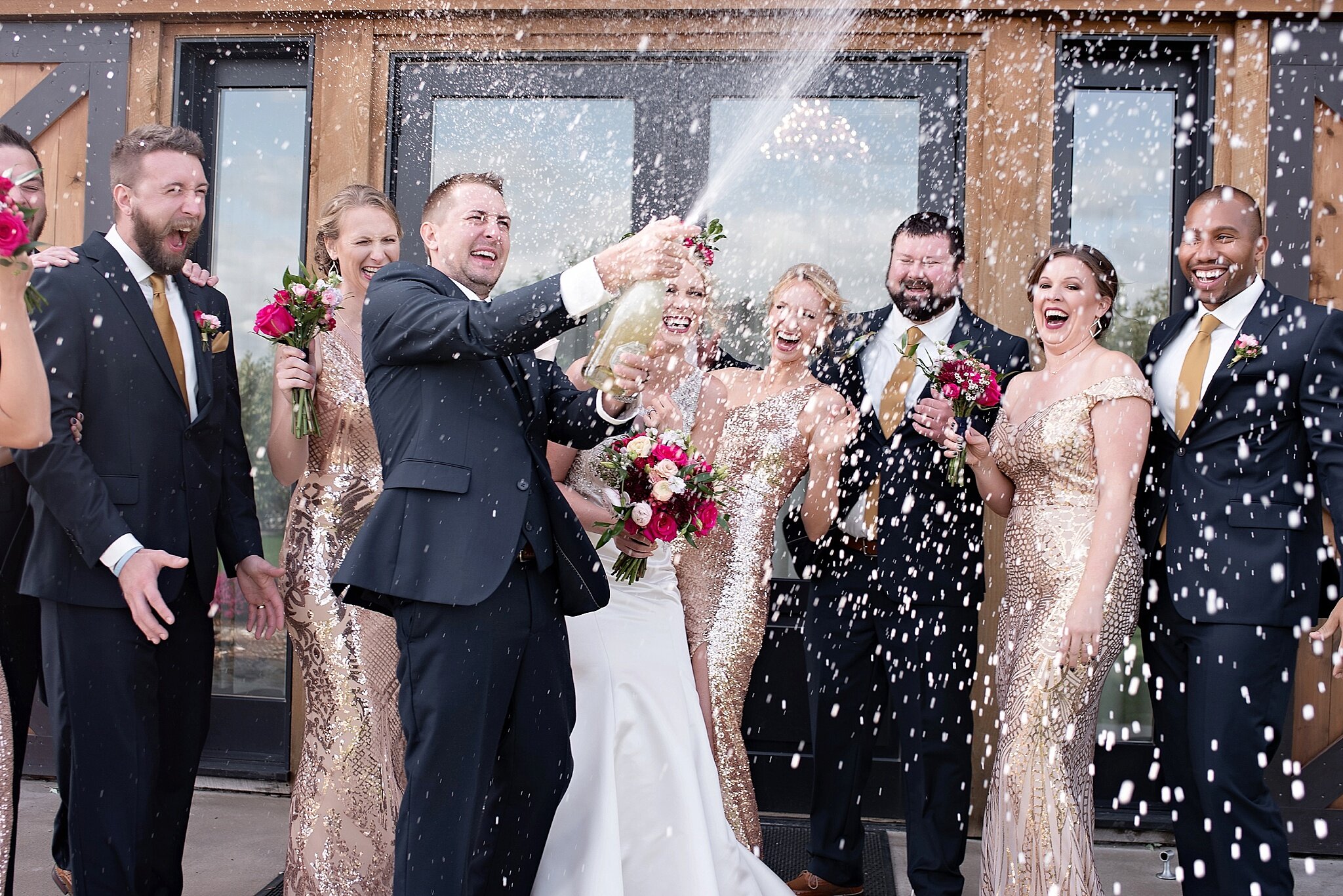 wedding party pops champagne to celebrate the bride and groom