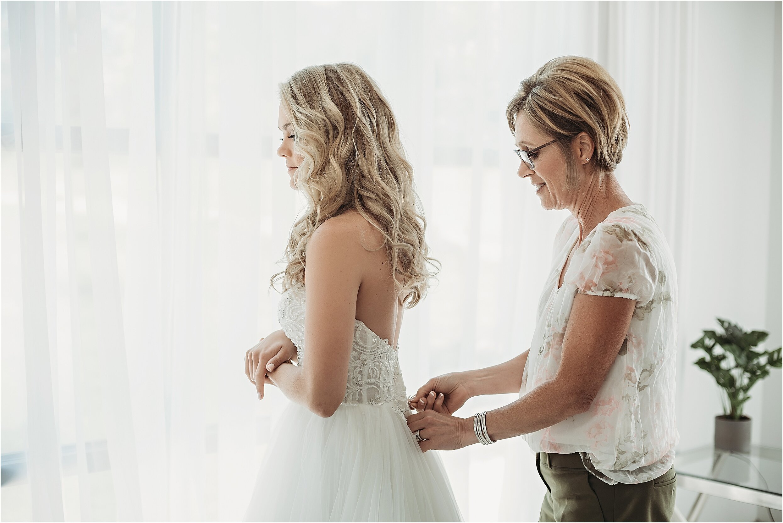 mom helps bride into her strapless wedding gown