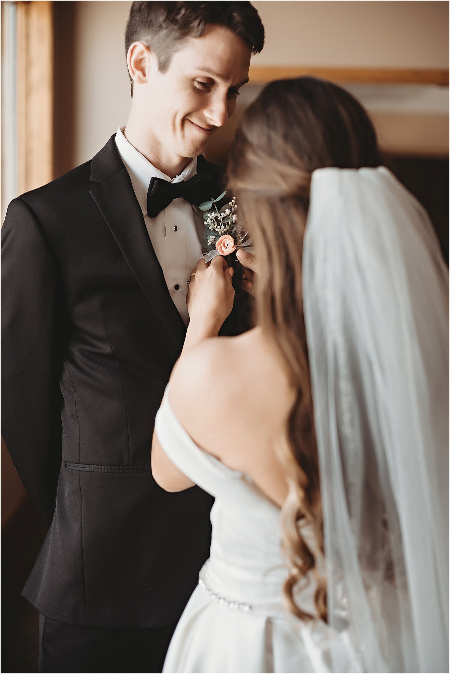 bride pins boutonniere on groom before wedding