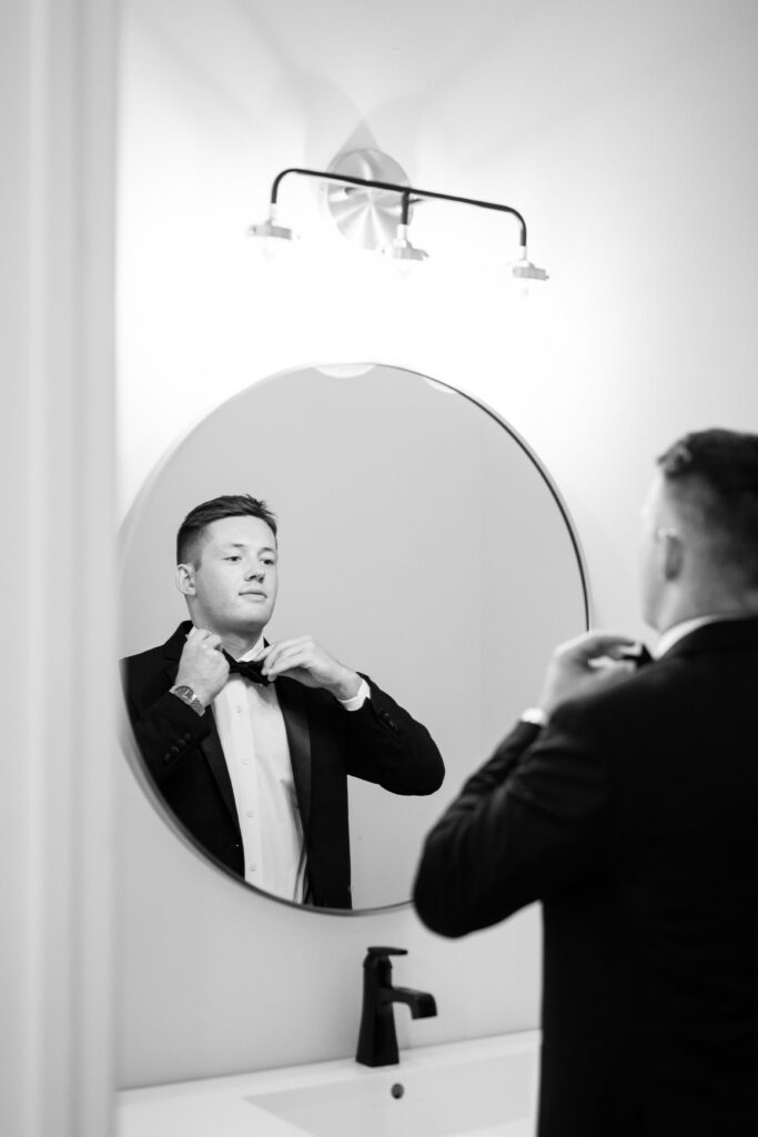 Groom adjusting tie at The Atrium at Blue Haven