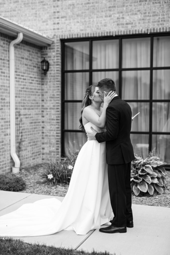 Bride and groom kiss in front of The Atrium at Blue Haven
