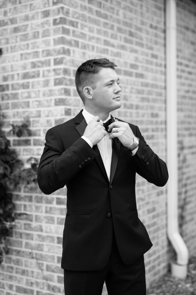 Groom adjusts tie at The Atrium at Blue Haven